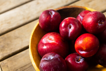 High angle close-up of fresh peaches in bowl over wooden table