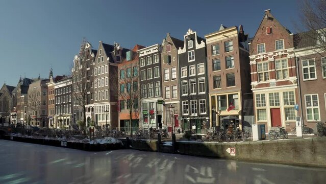 Frozen Oudezijds Voorburgwal canal in the Red-light district of De Wallen, covid 19 pandemic lockdown with an empty street, Amsterdam, The Netherlands