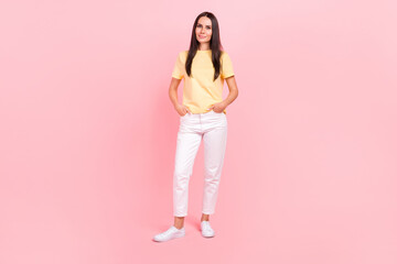 Fototapeta na wymiar Full length photo of cute sweet woman dressed yellow t-shirt hands pockets walking isolated pink color background