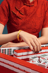 Woman in cheongsam playing mahjong(majiang), close-up, traditional Chinese mind game
