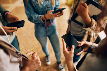 Close up of high school students using smart phones in hallway.