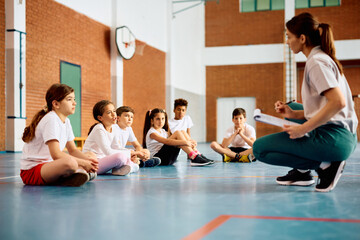 Elementary students communicating with their sports teacher during PE class.