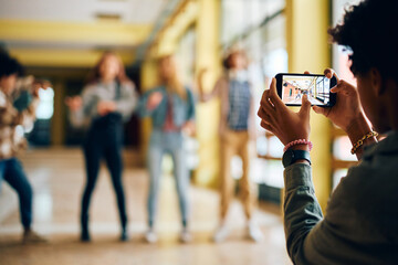 Close up of high school student takes picture of his friends with smart phone.