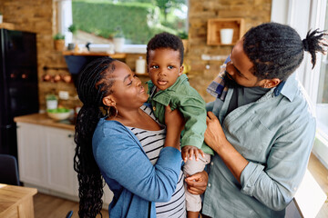 Happy African American parents with son in kitchen.