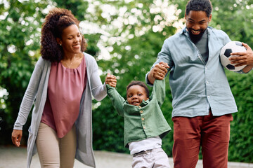 Playful black parents have fun with their small son outdoors.