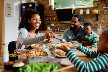 Happy African American family enjoying in meal at dining table.