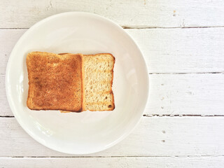 Toasts in a white plate placed on a wooden table.
