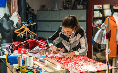 female seamstress cutting fabric in her sewing workshop