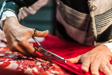 hands of female seamstress cutting fabric in her sewing workshop