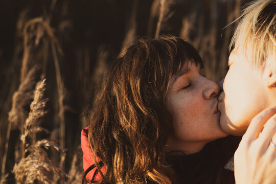 queer female couple kiss outdoors in golden nature and sunlight