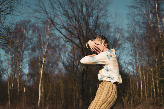 faceless image of androgynous dancer outside in winter sun and trees
