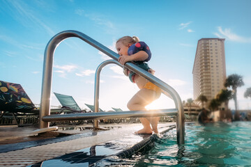Young girl getting out of pool at tropical beach family resort