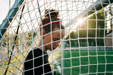 portrait of a girl stood in a football goal at sunset
