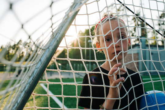 portrait of a girl stood in a football goal waiting to play