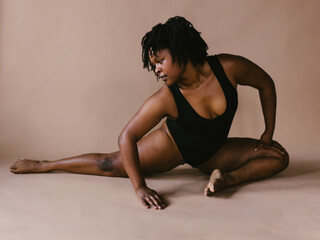 Woman black dancer in half split stretch dance pose in studio