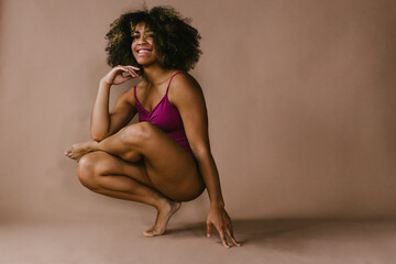 Female black dancer poses on foot with big smile and curly hair