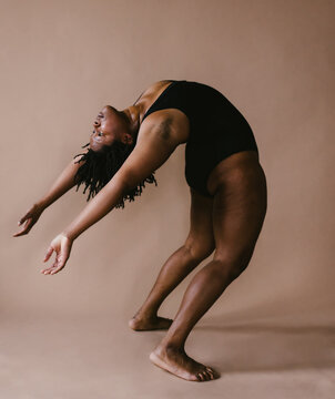 Black female dancer leans back to backbend in dance pose