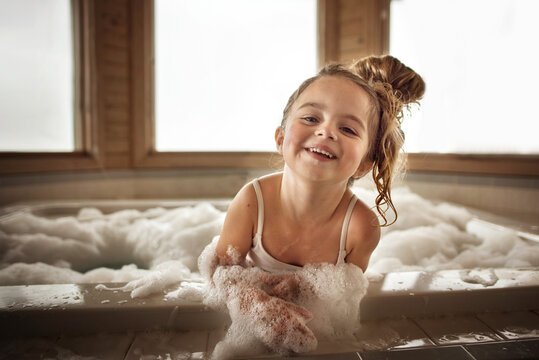 Cute little girl playing and laughing in bubble bath
