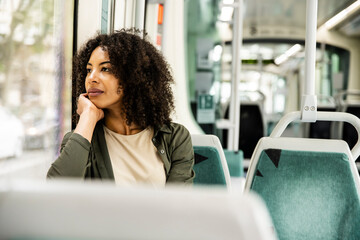 young woman commuting sitting and looking out the window.
