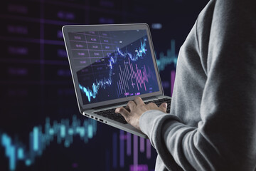 Close up of hands using laptop with glowing candlestick forex chart on blurry background. Investment, profit and financial growth concept. Double exposure.