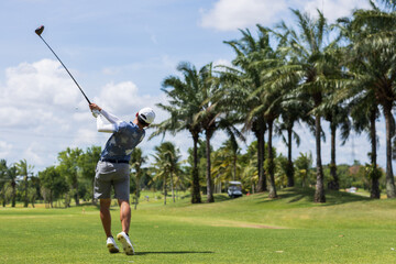 Obraz premium Golfer he's golfing in sunlight. View from the back. Backswing on teeing ground.