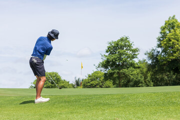 Golfers chipping a golf ball onto the green.