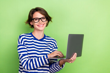 Photo of toothy beaming intelligent girl short haircut dressed sailor long sleeve holding laptop isolated on green color background