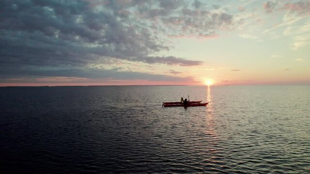 Aerial Shot of a Young Couple Paddling in Red Sea Kayak on the open Sea in Finland, Vaasa, Archipelago, Beautiful Peaceful Summer Sunset Atmosphere, Camera Fix