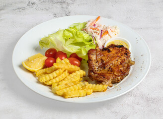 grilled chicken chop with lemon, salad, tomato and dip served in dish isolated on banana leaf top view of singapore food