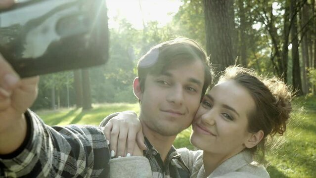 Girl and boy posing in front of camera. They are walking somewhere outdoor in the park. That’s their romantic date.