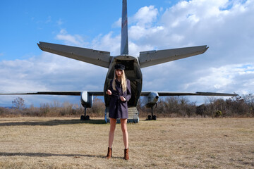 Young and beautiful blonde stewardess by the old cargo plane