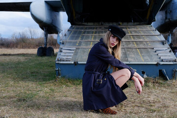 Young and beautiful blonde stewardess by the old cargo plane