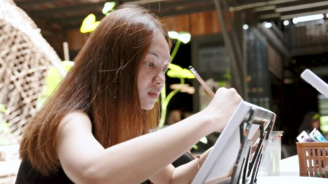 Beautiful young Asian girl, have fun with painting coloring activities, This is an activity that she loves always enjoys doing, always finds place with good atmosphere tells story images well.