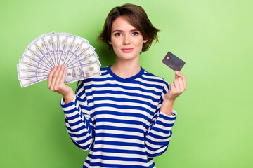 Photo of pleasant pretty girl with short haircut dressed sailor long sleeve hold plastic card dollars isolated on green color background