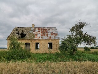 Old brick farmhouse in the countryside with storm clouds in the sky.