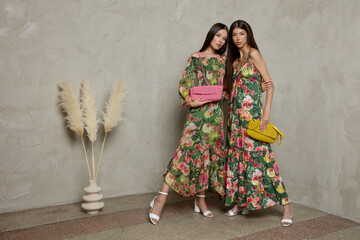 Two fashion asian models in identical looks, green dress with floral pattern, handbag, clutch....