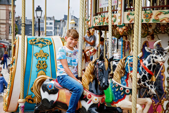 School kid boy having a ride on the old vintage merry-go-round in city of Honfleur France. Preteen child having fun.