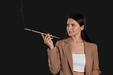 Obraz premium Woman using long cigarette holder for smoking on black background