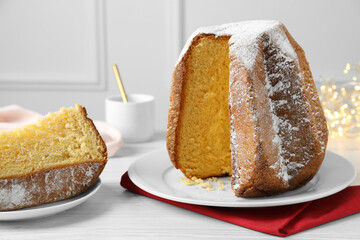 Delicious Pandoro cake decorated with powdered sugar on white wooden table. Traditional Italian pastry