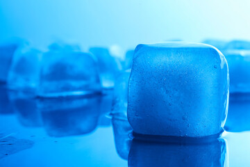 Crystal clear ice cubes on light blue background, closeup. Color tone effect