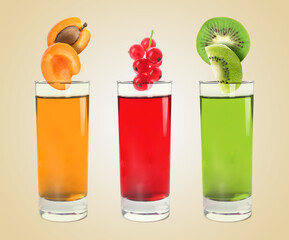 Different freshly made juices on beige background. Fruits falling into glasses