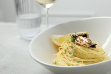 Tasty capellini with mussels and lemon served on light grey table, closeup. Exquisite presentation of pasta dish