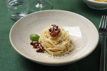 Tasty spaghetti with sun-dried tomatoes and parmesan cheese served on table, closeup. Exquisite presentation of pasta dish