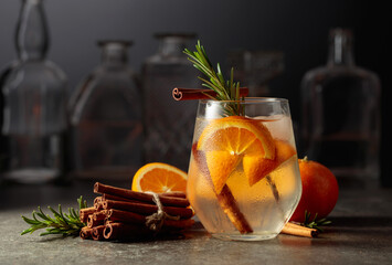 Cocktail gin tonic with ice, rosemary, cinnamon, and orange.
