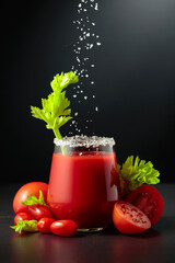 Sea salt is poured into a glass of tomato juice with celery.