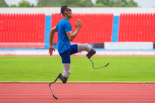 An Asian speed runner athlete with two prosthetic blades is captured practicing his speed running on the stadium's track