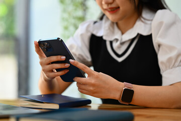 Young smiling woman using smartphone, checking social media, texting, browsing internet for shopping