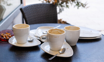 dirty dishes and an ashtray with cigarette butts on a table in a cafe
