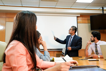 Indian business coach giving training to employees group at meting hall