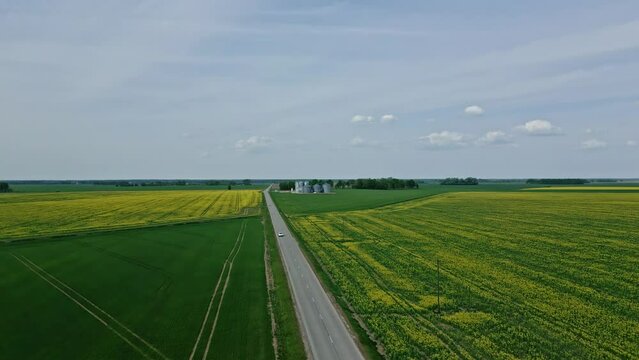 A car and truck driving along a road in farmland countryside - aerial